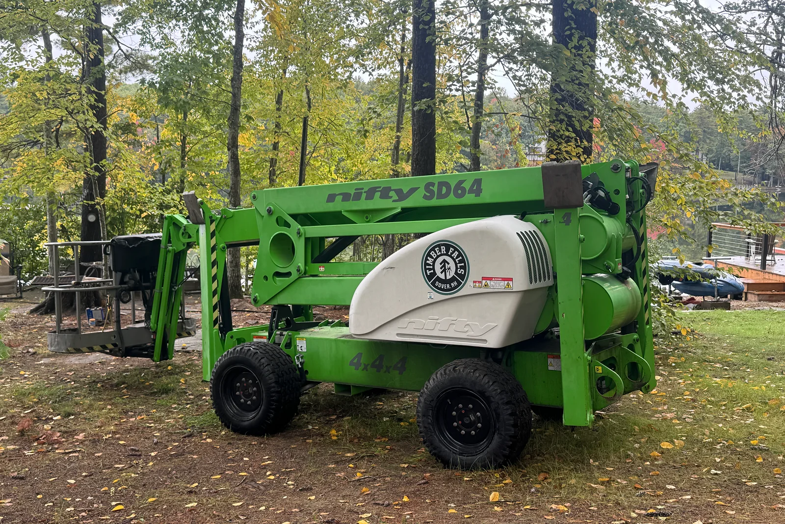 Timber Falls compact lift staged among trees at a jobsite