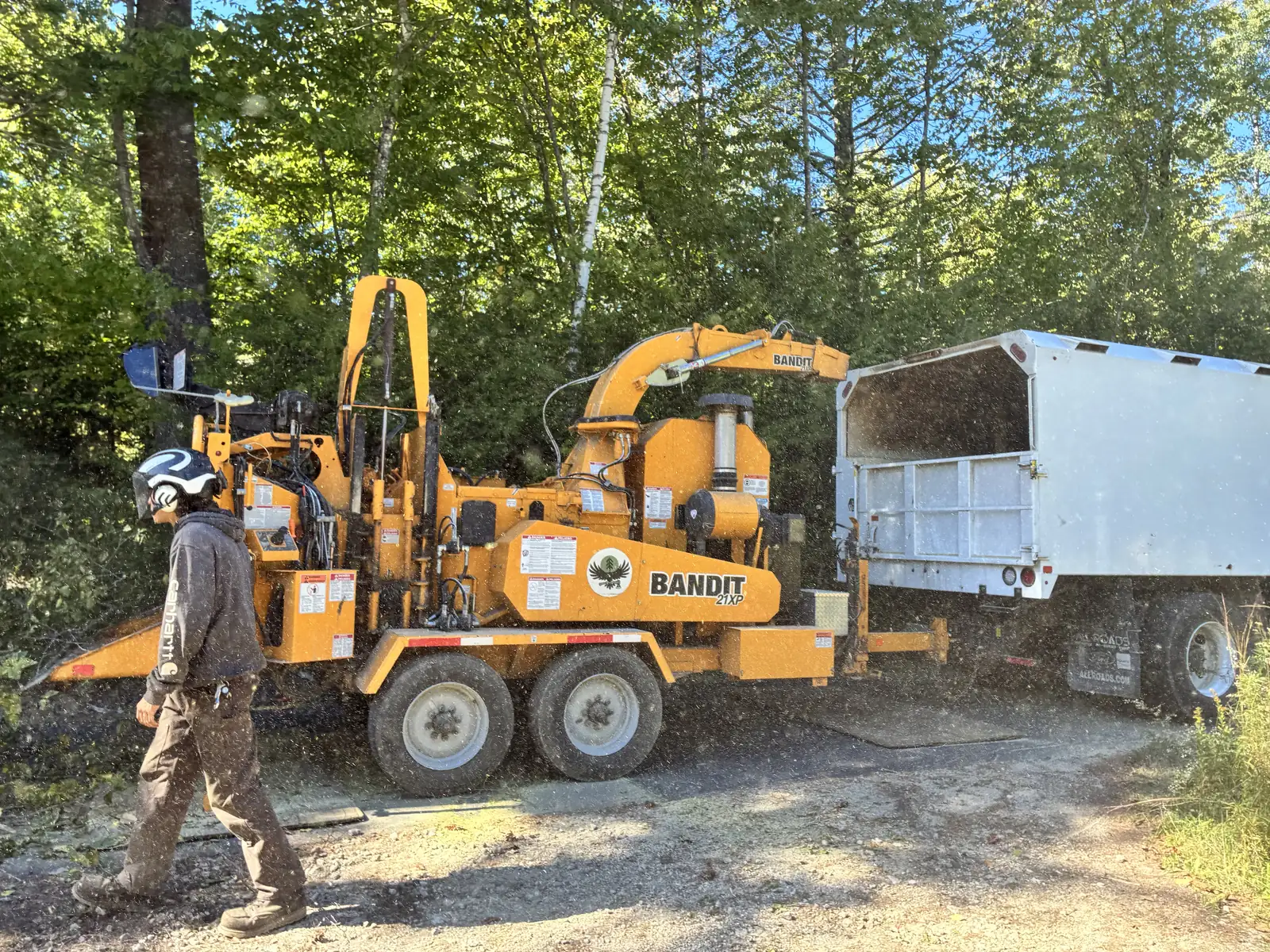 Helmeted Timber Falls crew member beside a chipper and debris truck