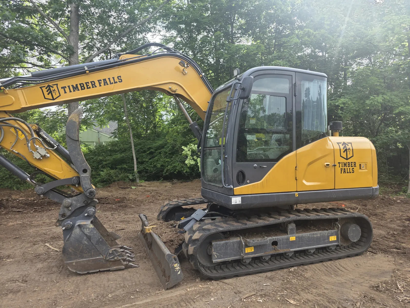 Yellow excavator with Timber Falls branding on its boom and cab