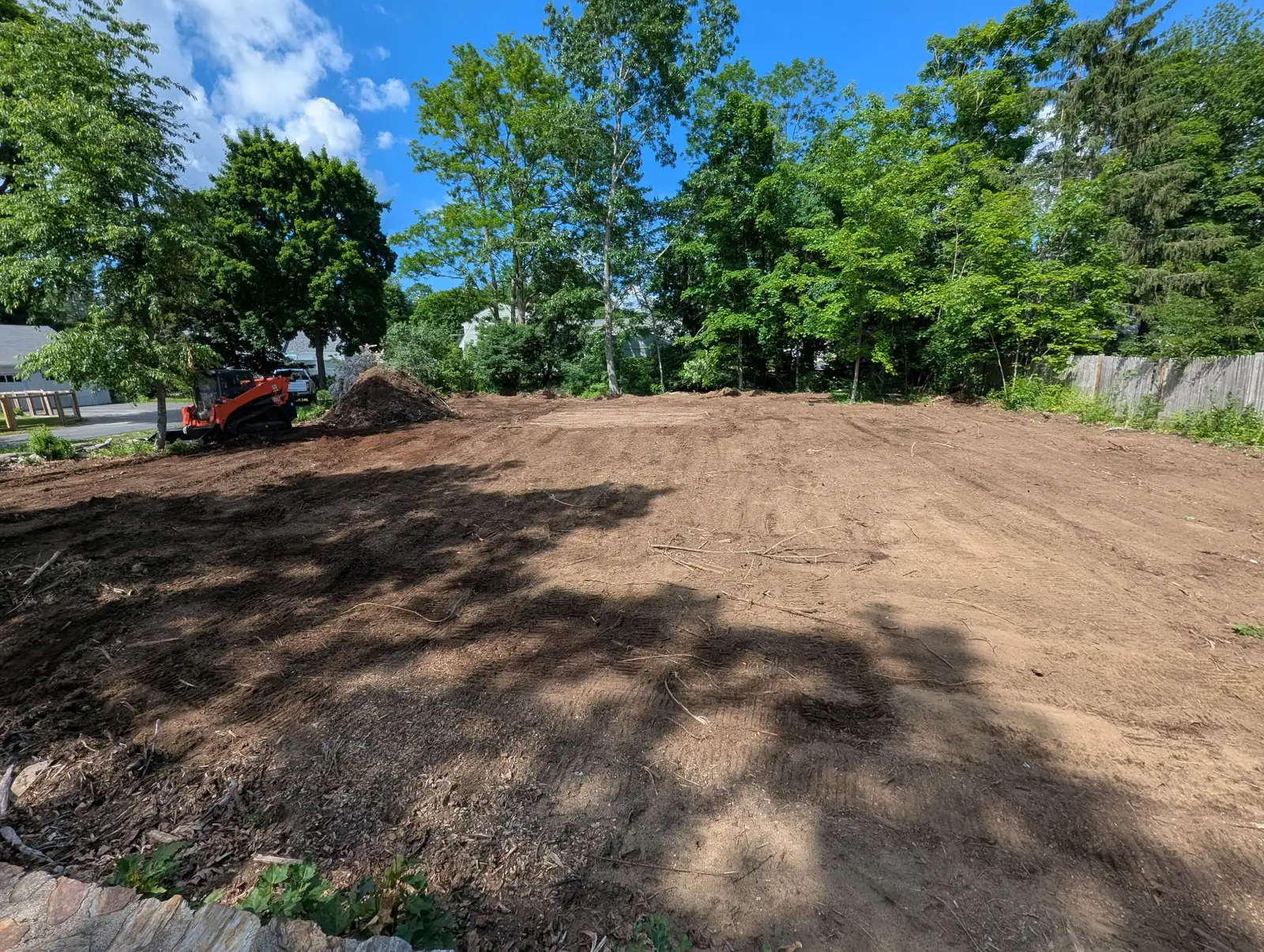 Prepared residential ground with a compact loader at the edge of the site