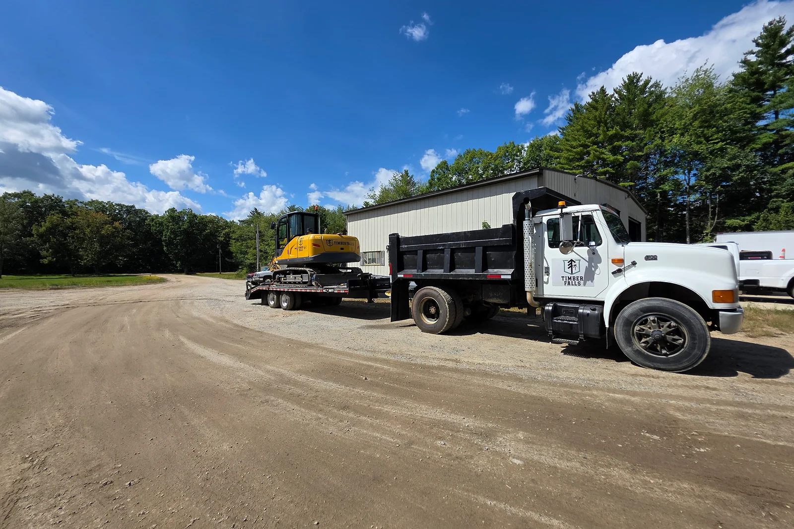 Timber Falls branded truck and excavator on a trailer
