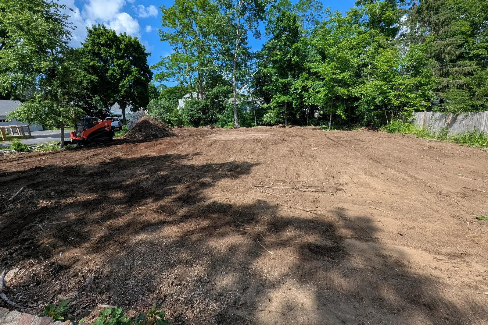 Compact loader beside graded ground at a Timber Falls property-services site