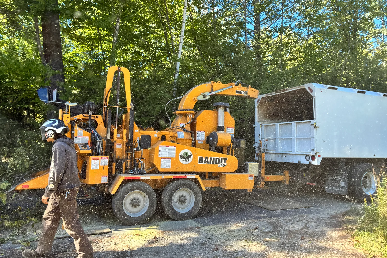 Timber Falls crew member working beside a wood chipper and debris truck